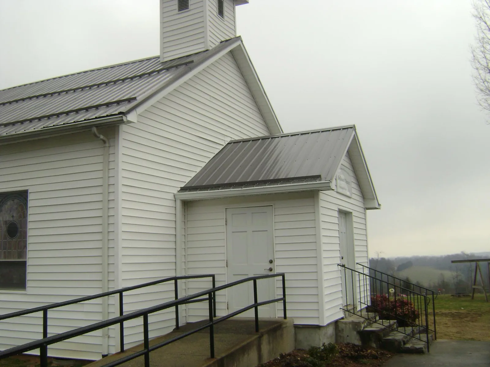 Gray metal roof on a white clapboard church with a steeple in Manilla